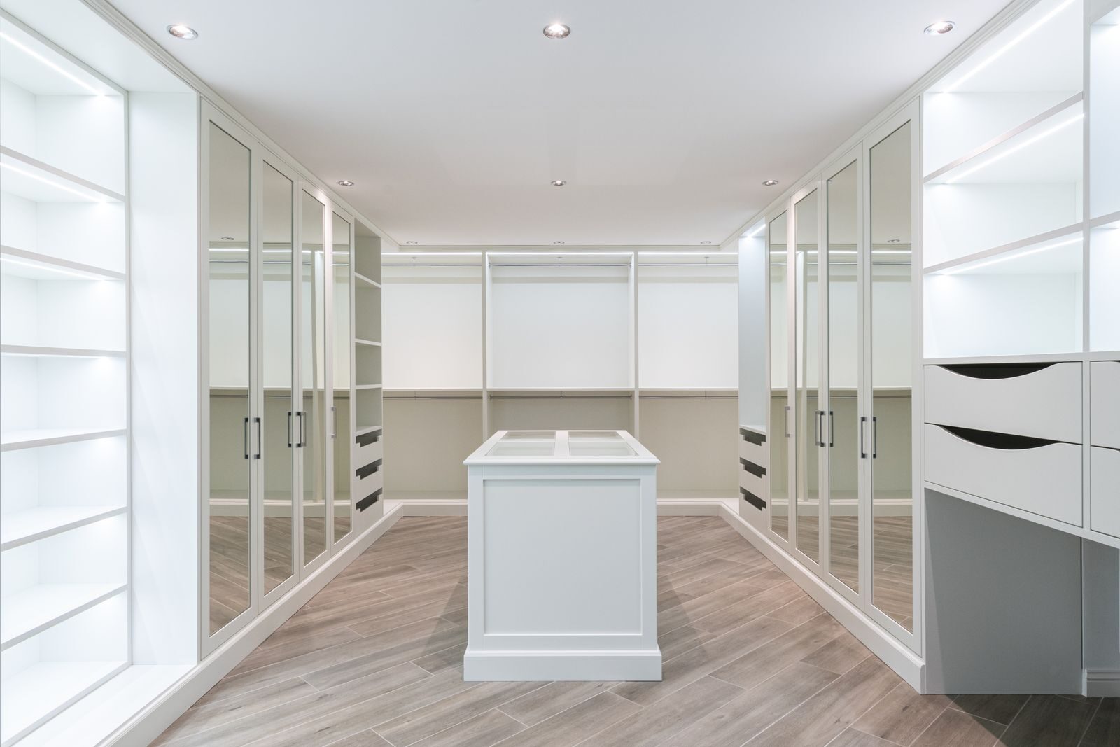 Interior of spacious minimalist walk in closet with empty shelves and mirrored doors in modern apartment